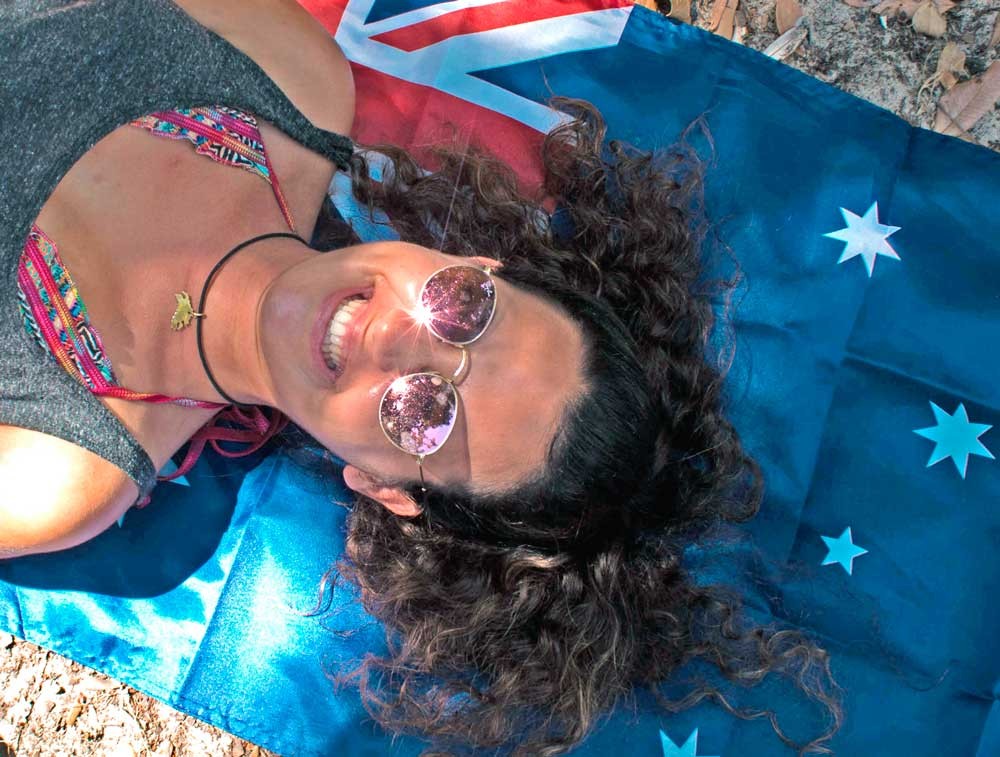 chica morena encima de una bandera de Australia estirada en el suelo