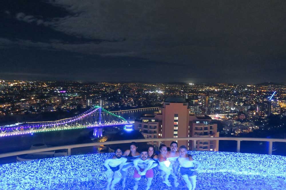 grupo de amigos dentro de una piscina y detrás una ciudad de noche