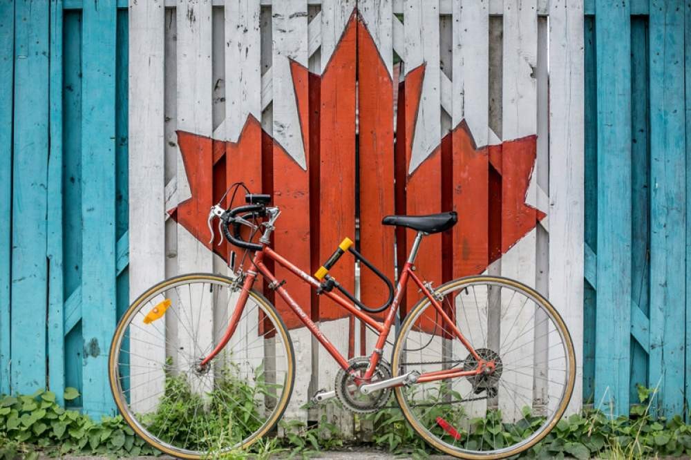 bicicleta apoyada en una pared con el dibujo de la hoja de Canadá de color rojo