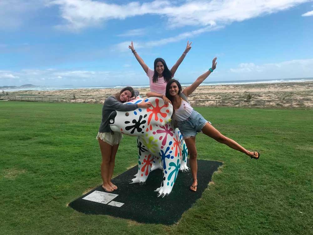 tres chicas encima de una figura de un animal sonriendo a cámara
