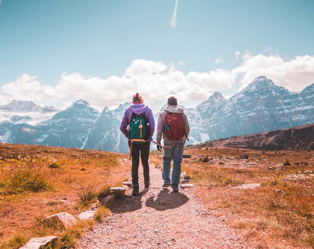 dos estudiantes de espaldas andando por la montaña 