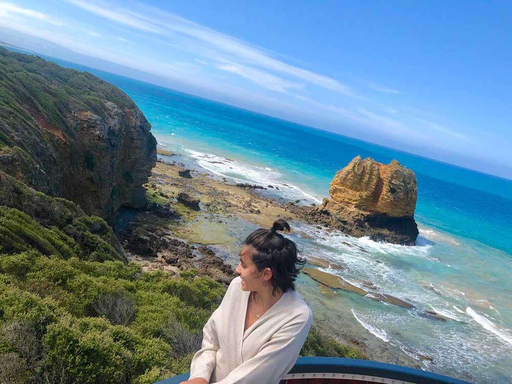 chica morena y detrás la playa y vegetación