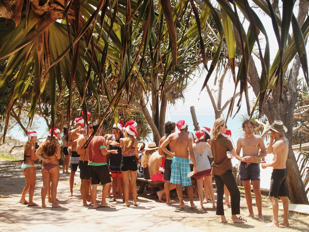 grupo de estudiantes que celebra la Navidad en Australia con gorritos y traje de baño hablando entre ellos en una playa de Sydney