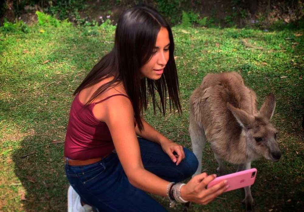 Animales en Australia chica morena haciéndose un selfie con un canguro