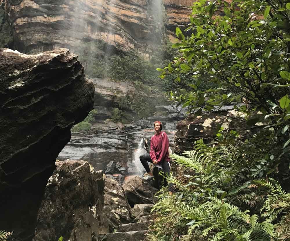 chica morena posando encima de una roca con la naturaleza