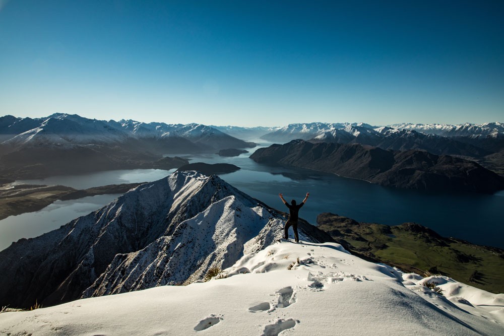 chico de espaldas y delante tiene un paisaje montañoso con un lago