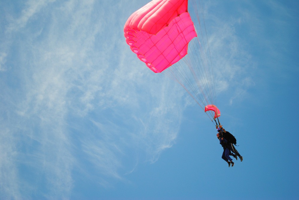 dos personas saltando en paracaídas de color rosa