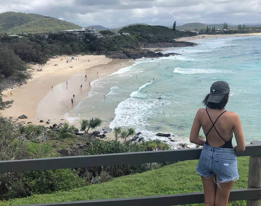 chica morena con una gorra de espaldas y delante la playa